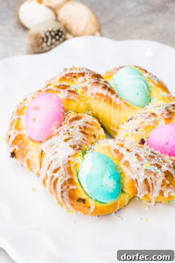 Italian Easter Bread Recipe with Video 4 A photo of Italian Easter bread with bright hard boiled eggs nestled in it, and covered in sprinkles and a sweet glaze.