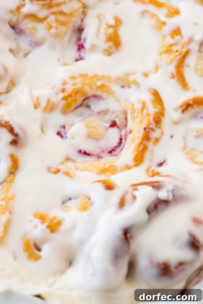 A photo of a pan of easy raspberry sweet rolls covered in frosting.