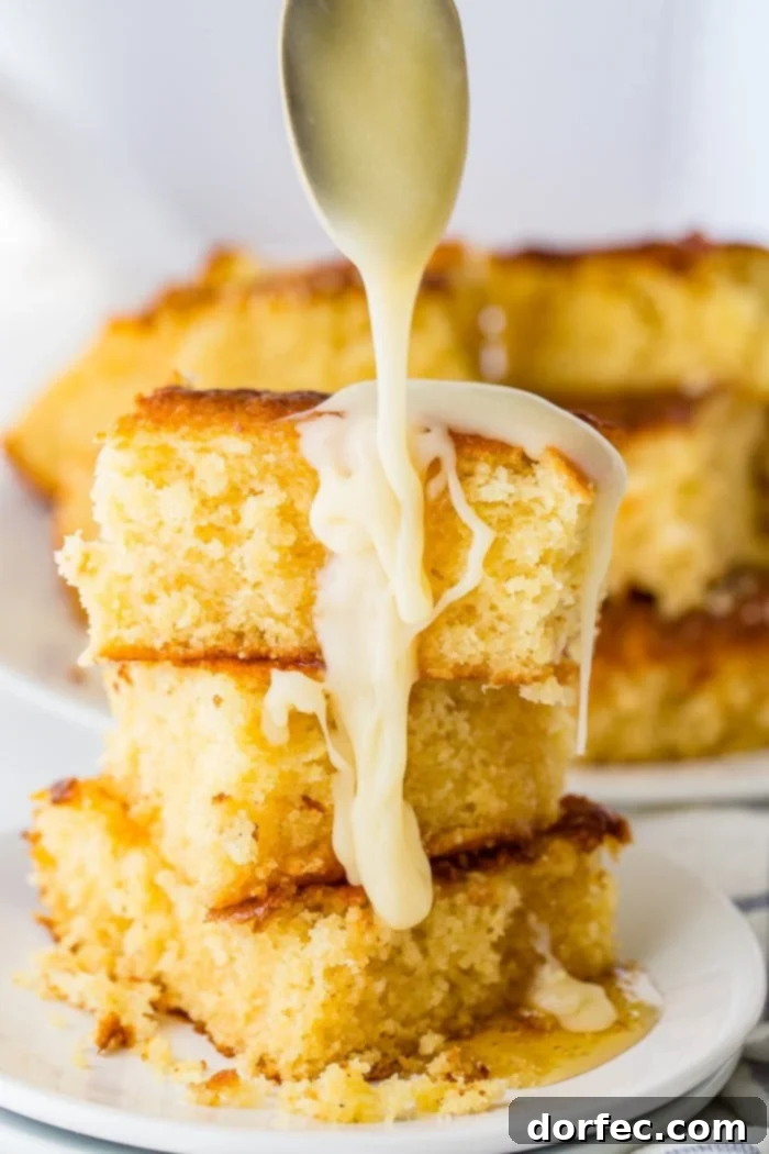 Three pieces of homemade sweet cornbread stacked and generously drizzled with honey butter.