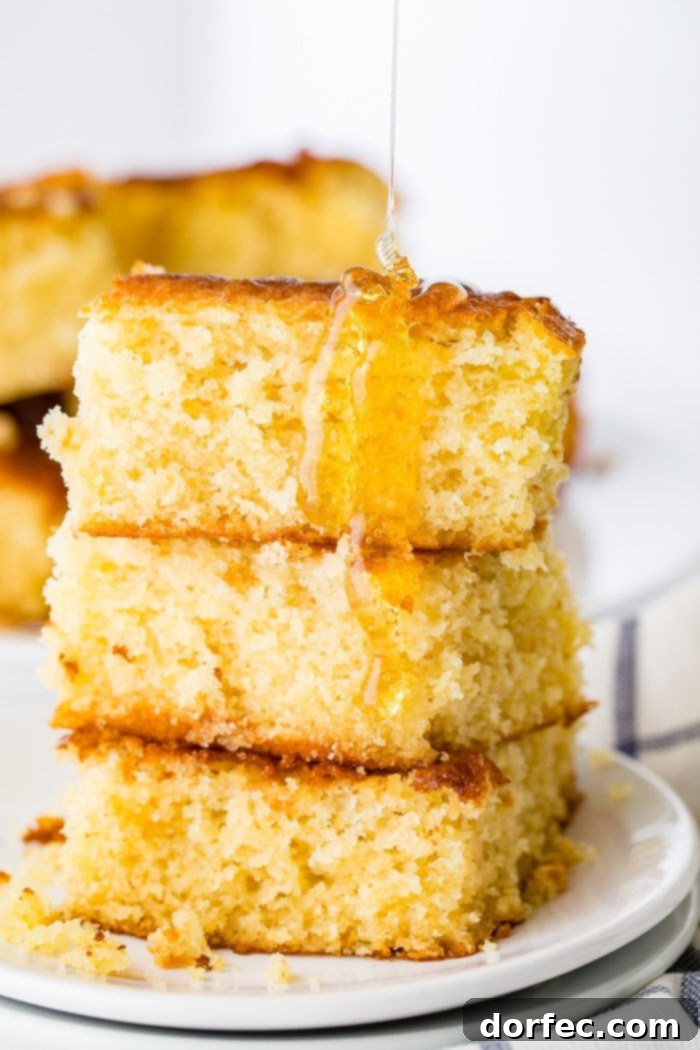 Three pieces of golden homemade cornbread, stacked and drizzled generously with honey.