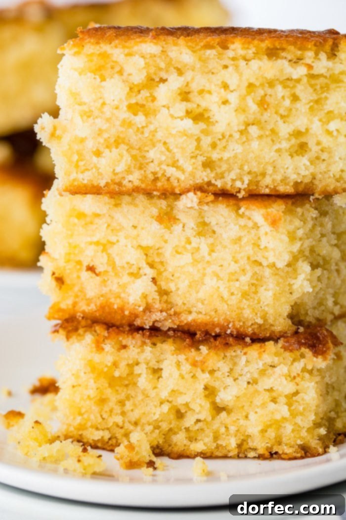 Three pieces of perfectly baked homemade cornbread stacked on a plate.
