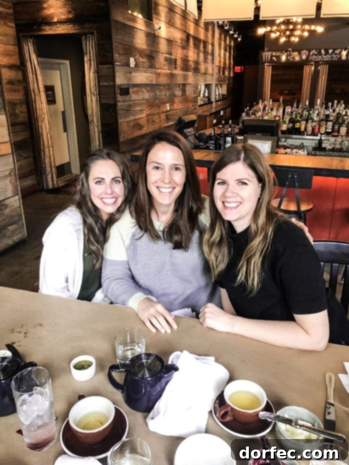 Road Trip Ready Smart Snacks and Fun Printables 12 Three friends sitting around a table at a restaurant, all smiling warmly at the camera, capturing a moment of camaraderie and shared enjoyment.