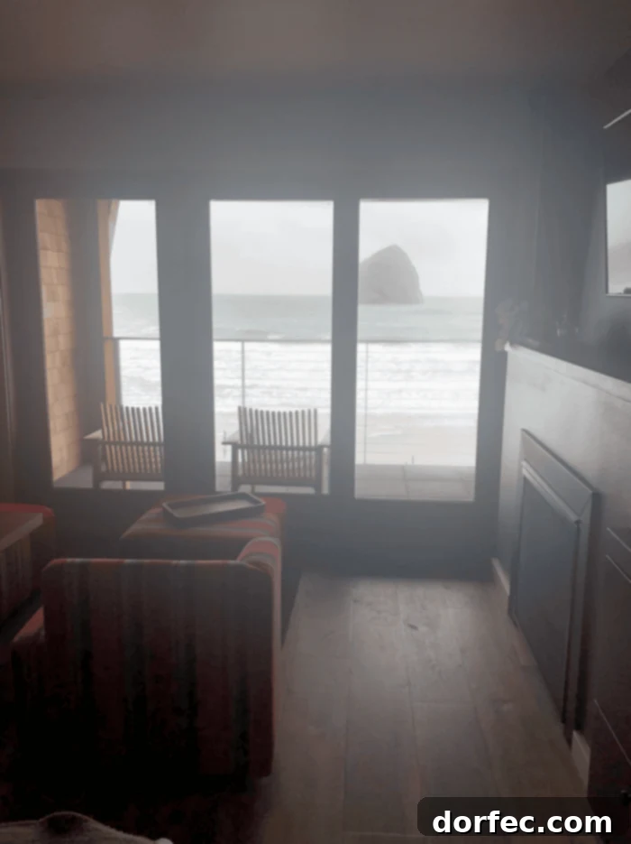 Road Trip Ready Smart Snacks and Fun Printables 8 A breathtaking photo captured from a hotel room window, showcasing the iconic Cannon Beach in Oregon. The serene scene features the vast ocean, the majestic Haystack Rock standing tall, and two inviting chairs on a patio, perfectly positioned for enjoying the coastal view.