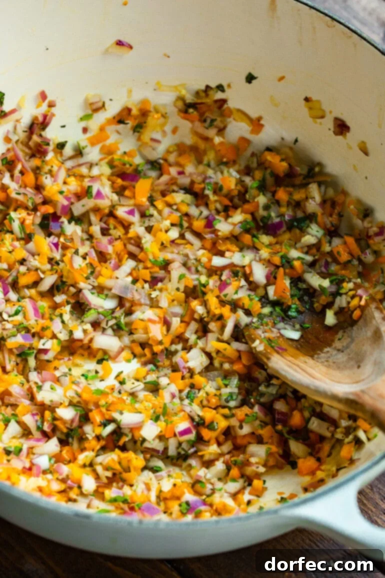 A Bowl of Lasagna Bliss 6 A close-up of vibrant minced red onions, garlic, bell pepper, and fresh green herbs gently sautéing in a ceramic Dutch oven, forming the aromatic base of the lasagna soup.