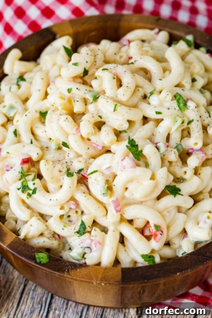 Ultimate Macaroni Pasta Salad Recipe 5 A close up picture of an ultra-creamy macaroni salad recipe with visible vegetables, appealing for summer cookouts.