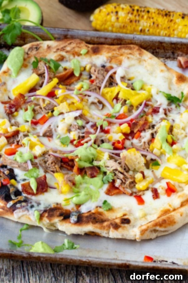 Pulled Pork Pizza with Sweet Corn and Cilantro Cream A photo of pulled pork pizza covered in sweet corn, red onions, pinapple, bacon, and fresh cilantro.
