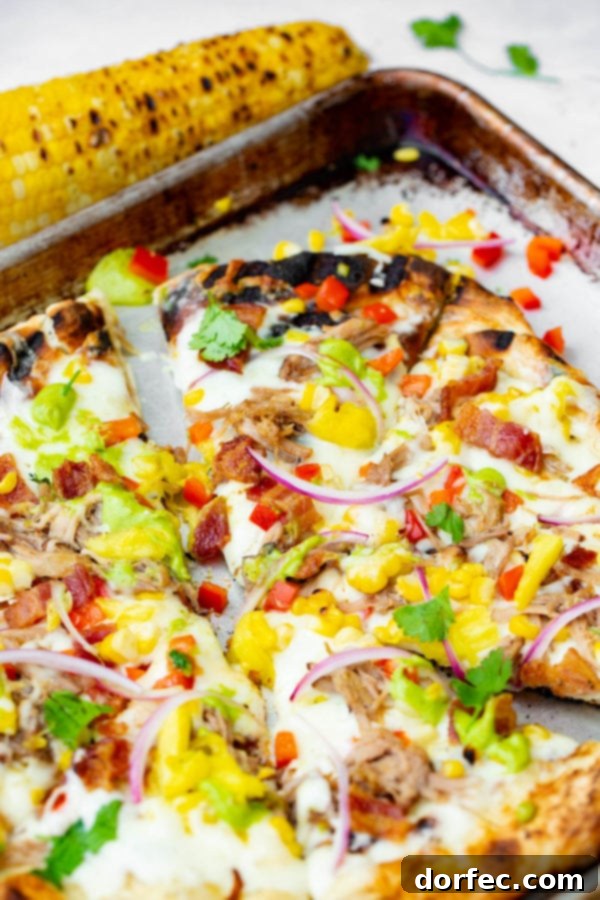 Pulled Pork Pizza with Sweet Corn and Cilantro Cream A photo of pulled pork pizza covered in sweet corn, red onions, pinapple, bacon, and fresh cilantro.