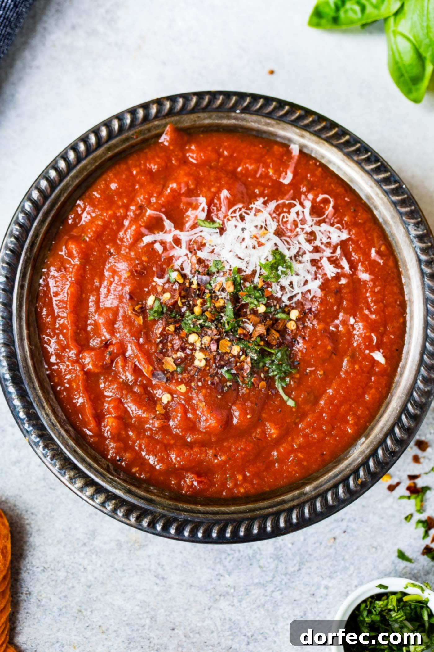 A bowl of homemade pizza sauce. Cheese and herbs are sprinkled on top.