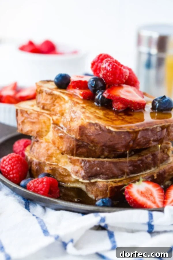Who Wants French Toast for Breakfast? A photo of French toast with a stack of golden, syrup-drenched French toast slices covered in fresh berries.