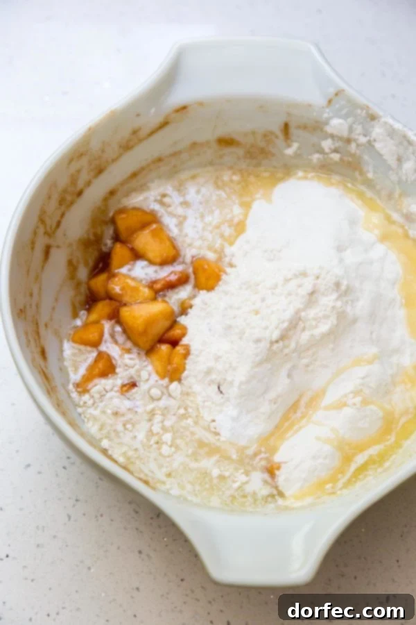 A close-up shot of fresh peach dump cake ingredients in a mixing bowl, showcasing diced peaches, flour, sugar, and other dry ingredients before mixing.
