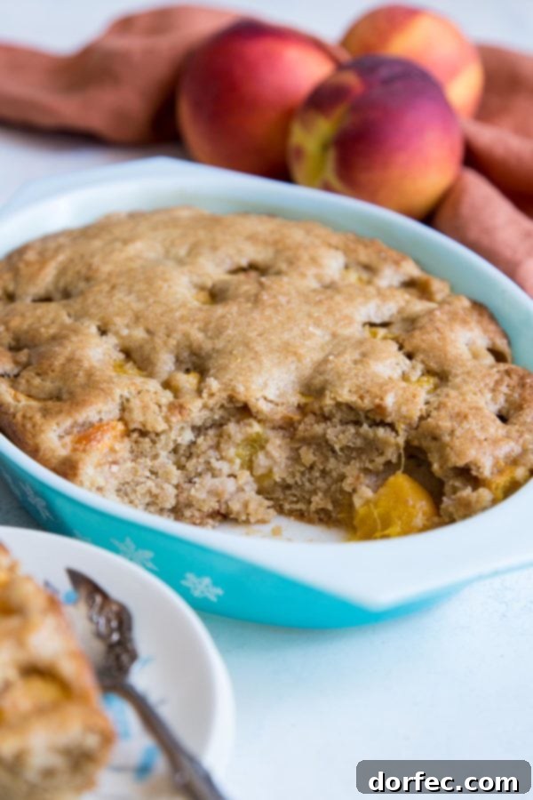 A warm, freshly baked peach dump cake in an oval Pyrex dish, with a perfectly golden-brown crust and bubbling peach filling.