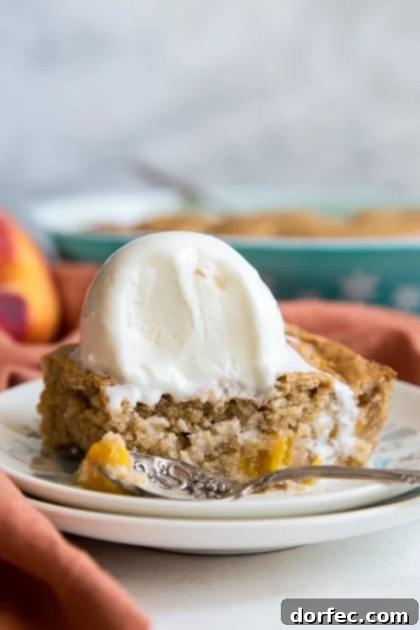 A serving of warm peach dump cake topped with a scoop of vanilla ice cream, creating a mouth-watering contrast of temperatures and textures.