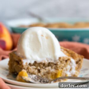 A beautifully baked peach dump cake, ready to be served, topped with a scoop of melting vanilla ice cream.