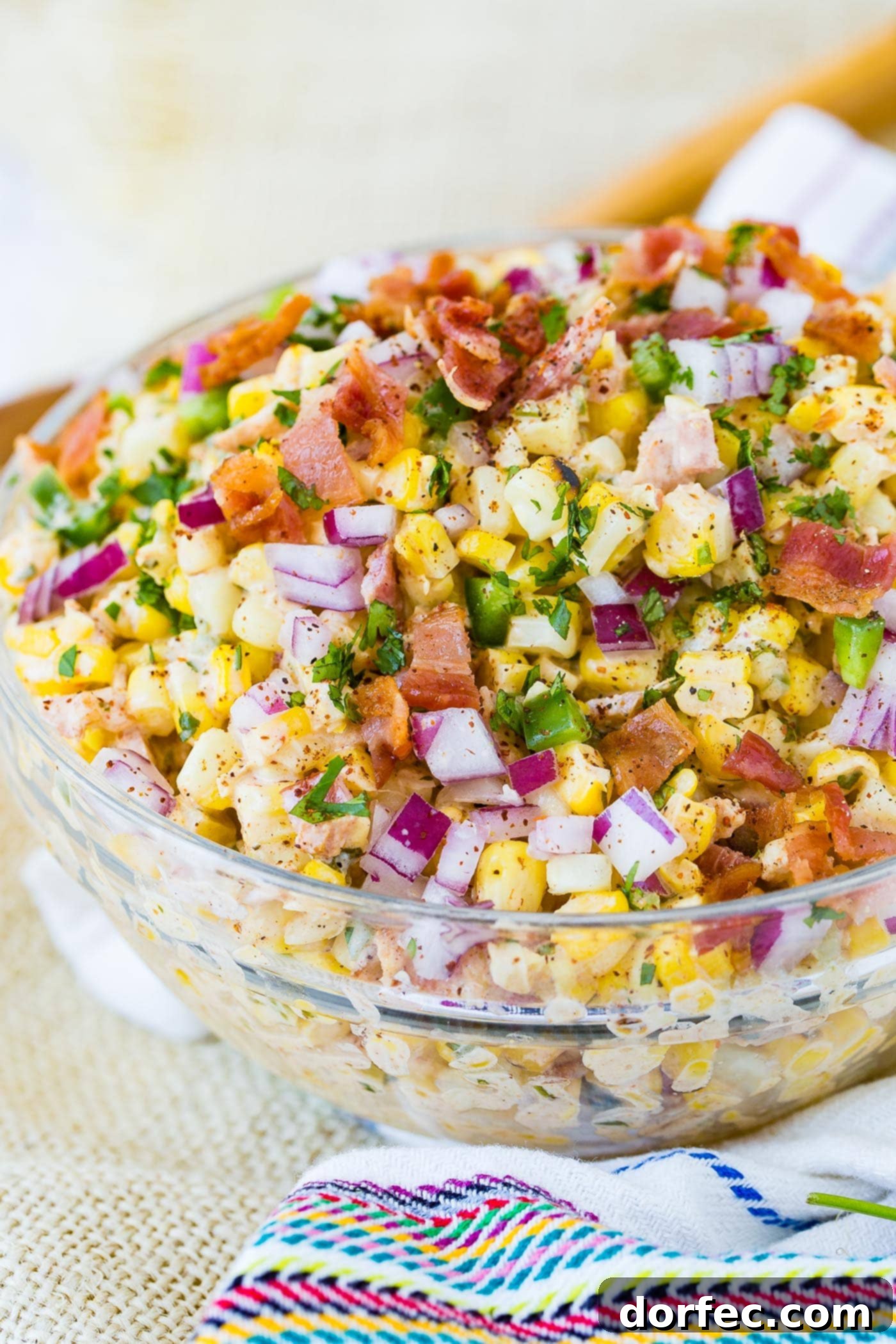 A bowl of Mexican corn salad topped with bacon and jalapeno.