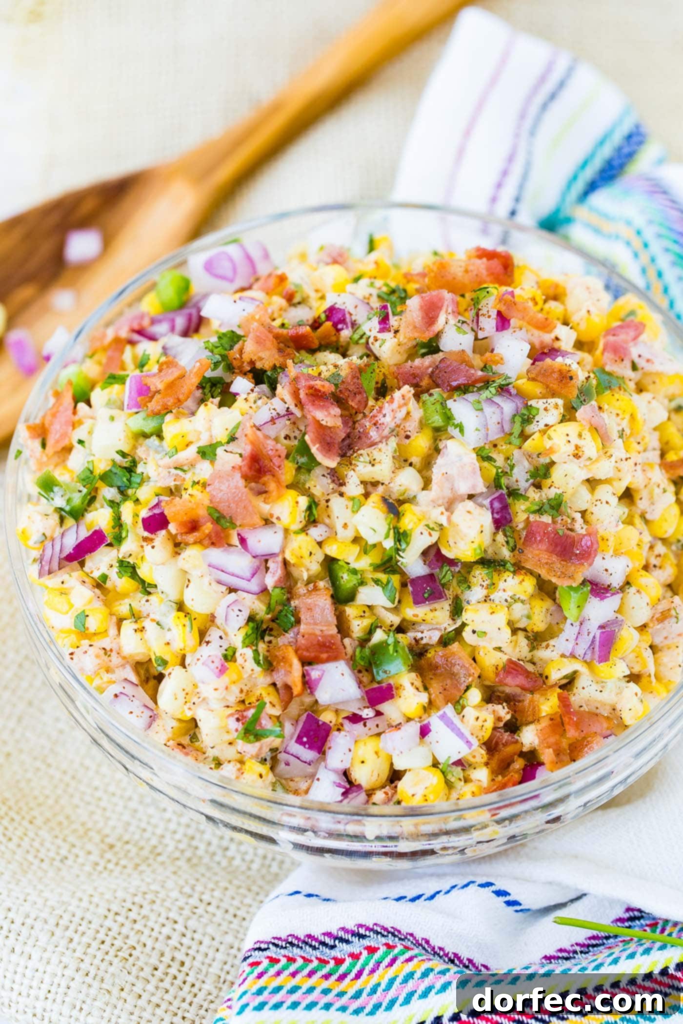 A bowl of Mexican corn salad topped with bacon and jalapeno.