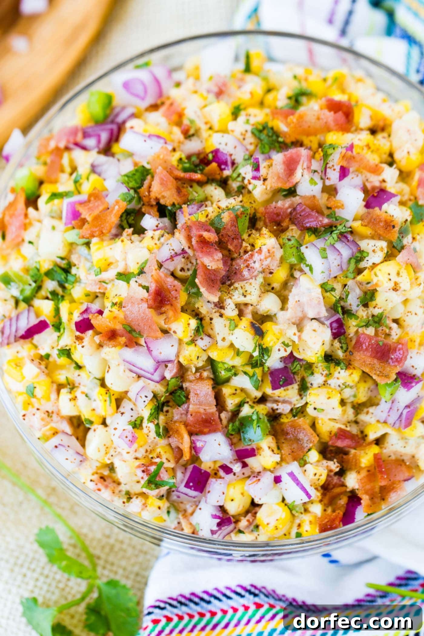 A bowl of Mexican corn salad topped with bacon and jalapeno.