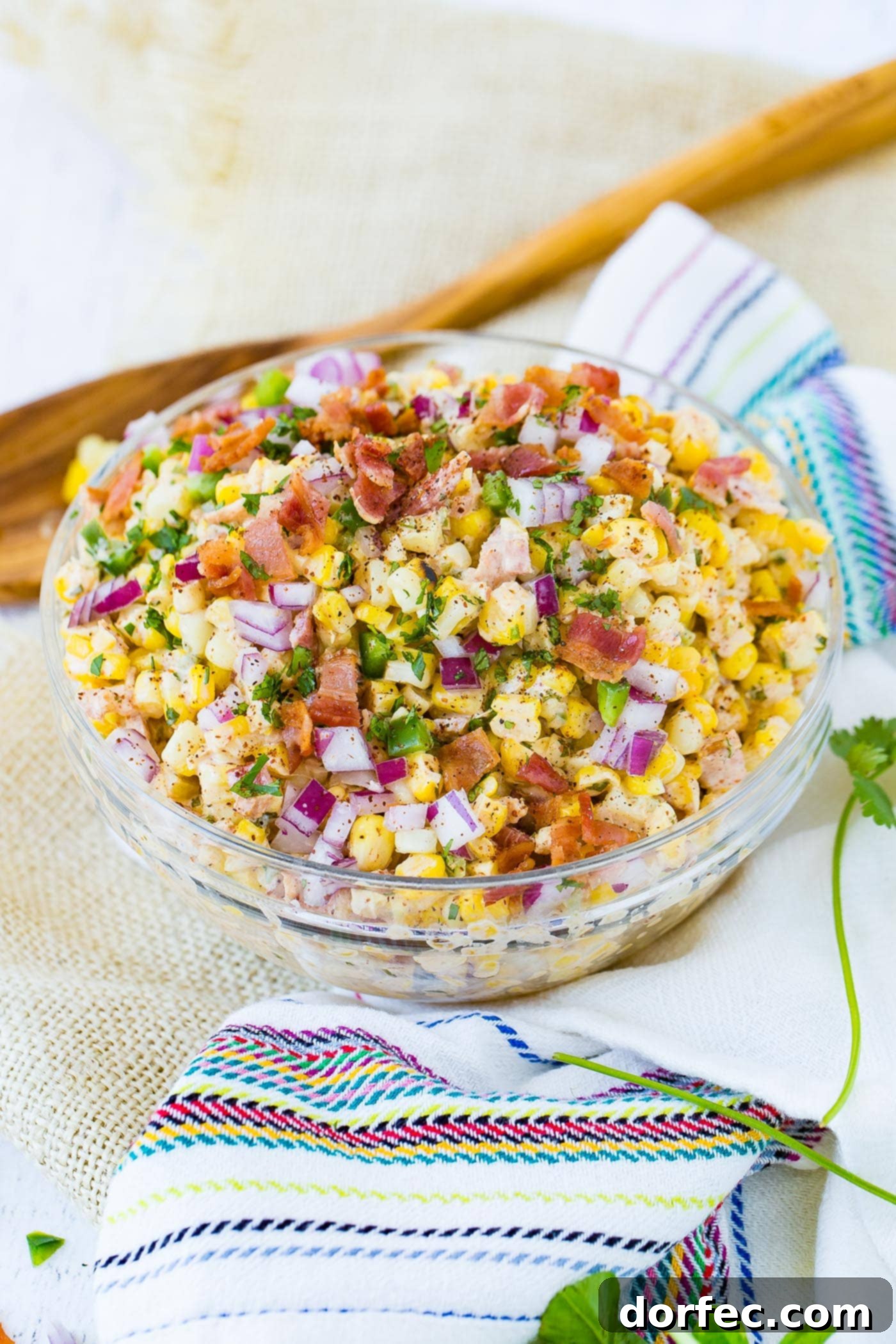 A bowl of Mexican corn salad topped with bacon and jalapeno.