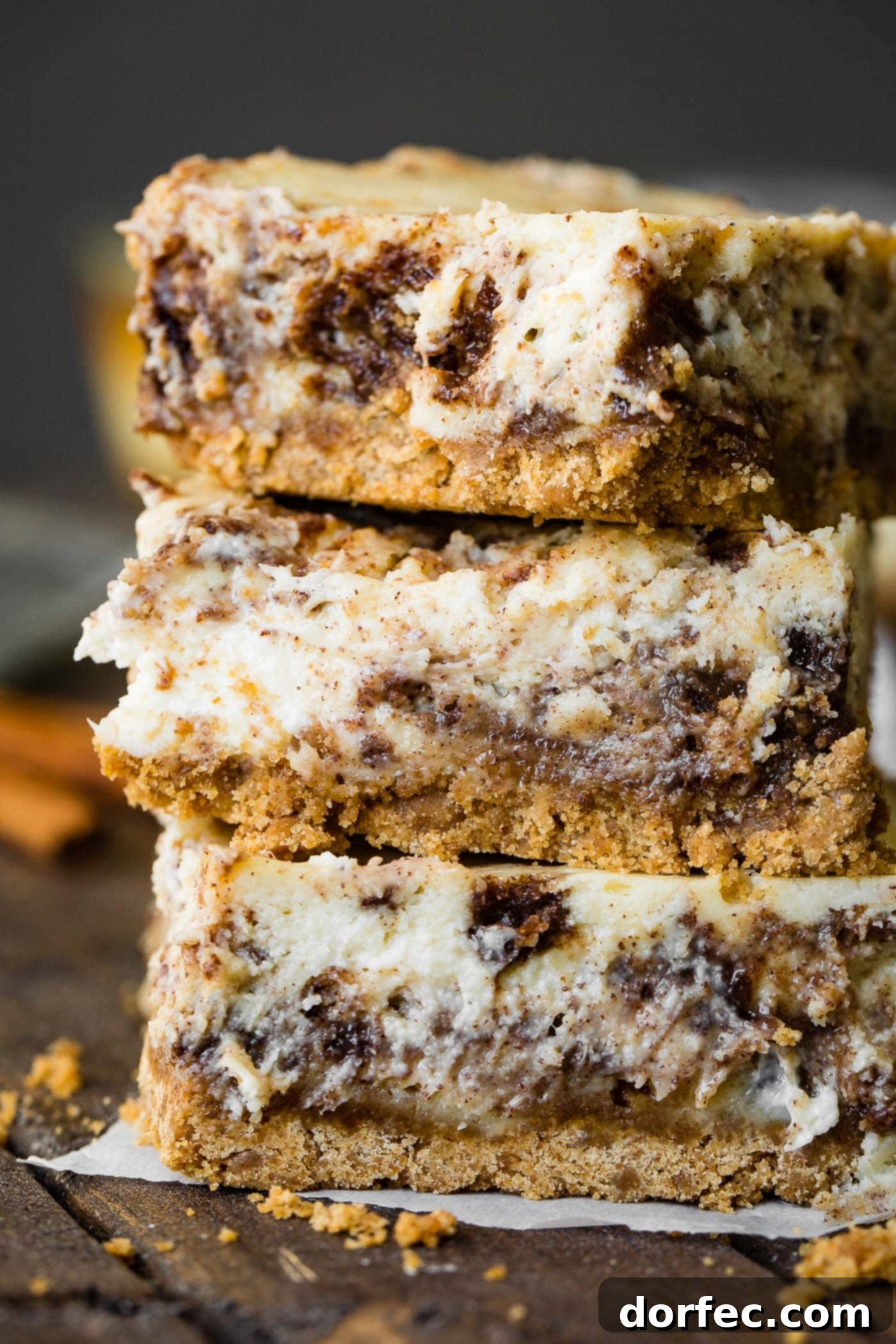 A photo of three cinnamon roll cheesecake bars stacked on top of each other, ready to be served.