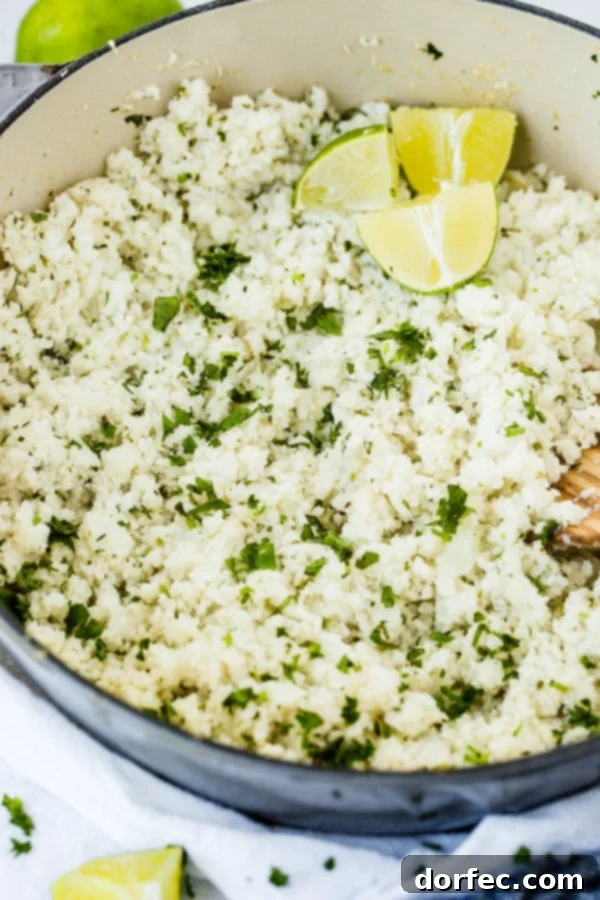A photo of a pot full of vibrant Cilantro Lime Cauliflower Rice with fresh lime wedges elegantly placed on top, ready to be served.