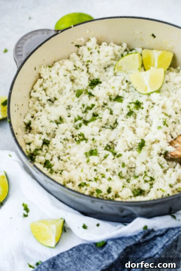 A photo of a pot brimming with Cilantro Lime Cauliflower Rice, garnished with fresh lime wedges and a wooden spoon, ready to be enjoyed.