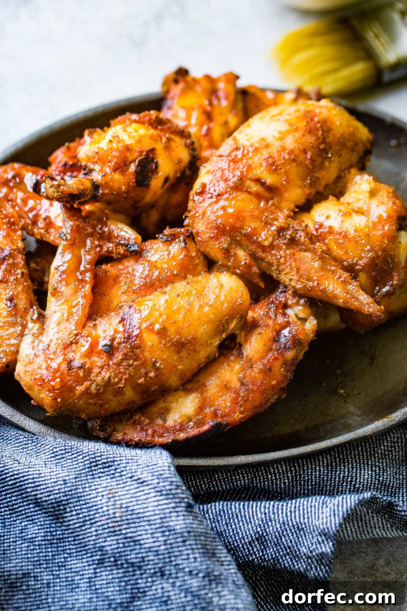 The BEST Dry Rubbed Smoked Chicken Wings A mouth-watering image of dry-rubbed smoked chicken wings piled high on a plate, showcasing their crispy skin and rich color.