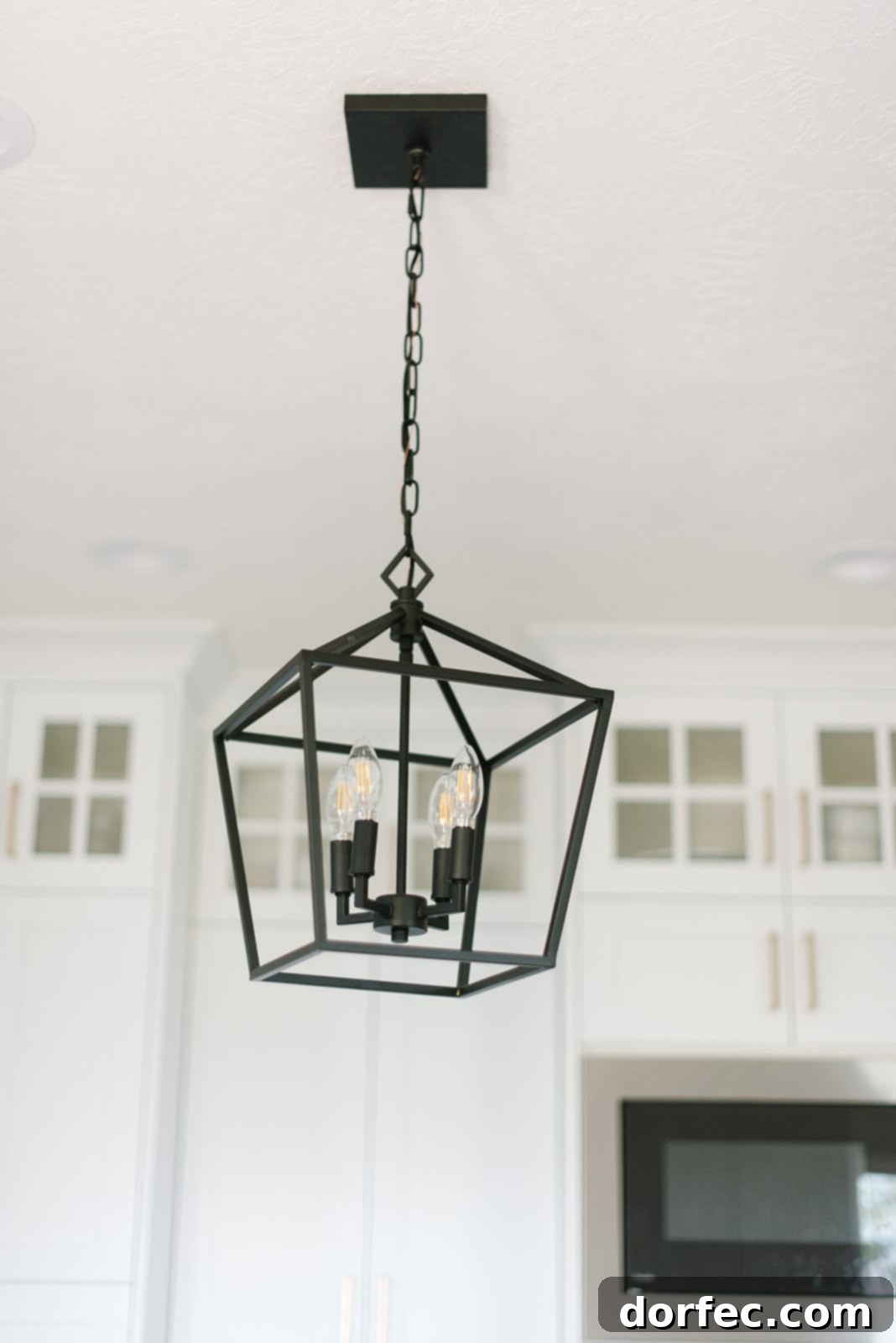 Detailed shot of the all-white kitchen's custom cabinetry and sophisticated lighting fixtures