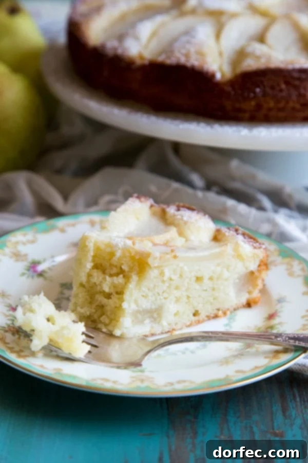 A slice of Italian pear cake on a plate, showcasing its tender texture and fresh pear pieces