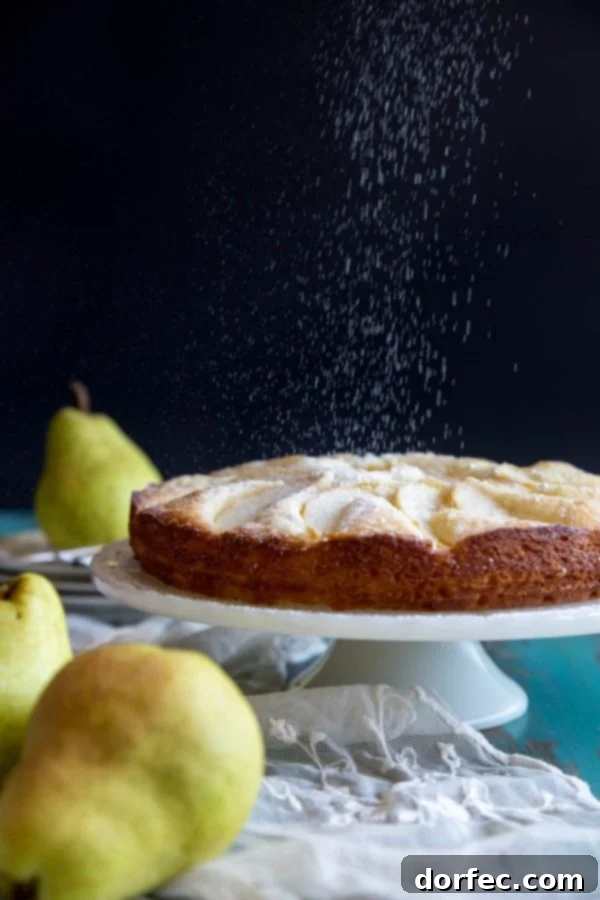 Dusting powdered sugar on a baked Italian pear cake, for a beautiful finish