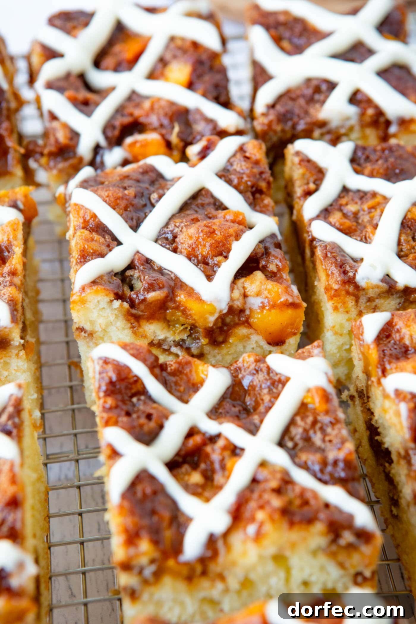 Several slices of easy peach sour cream coffee cake, each adorned with a sweet glaze, are arranged beautifully.