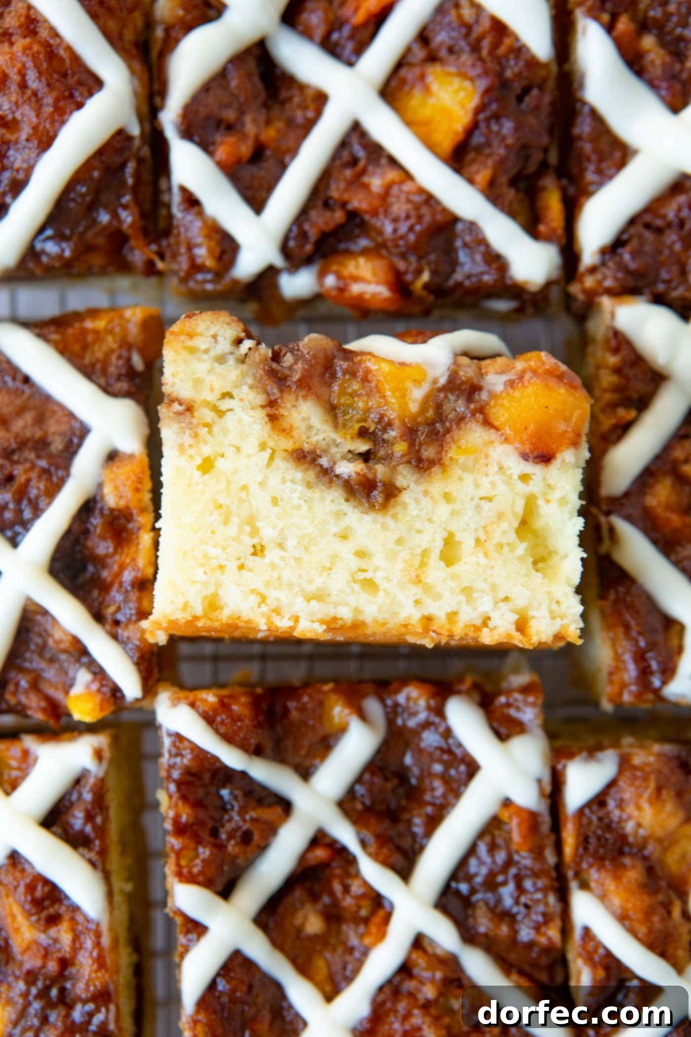An overhead view of several pieces of peach coffee cake with a sweet glaze, with one slice turned on its side to show the moist interior.