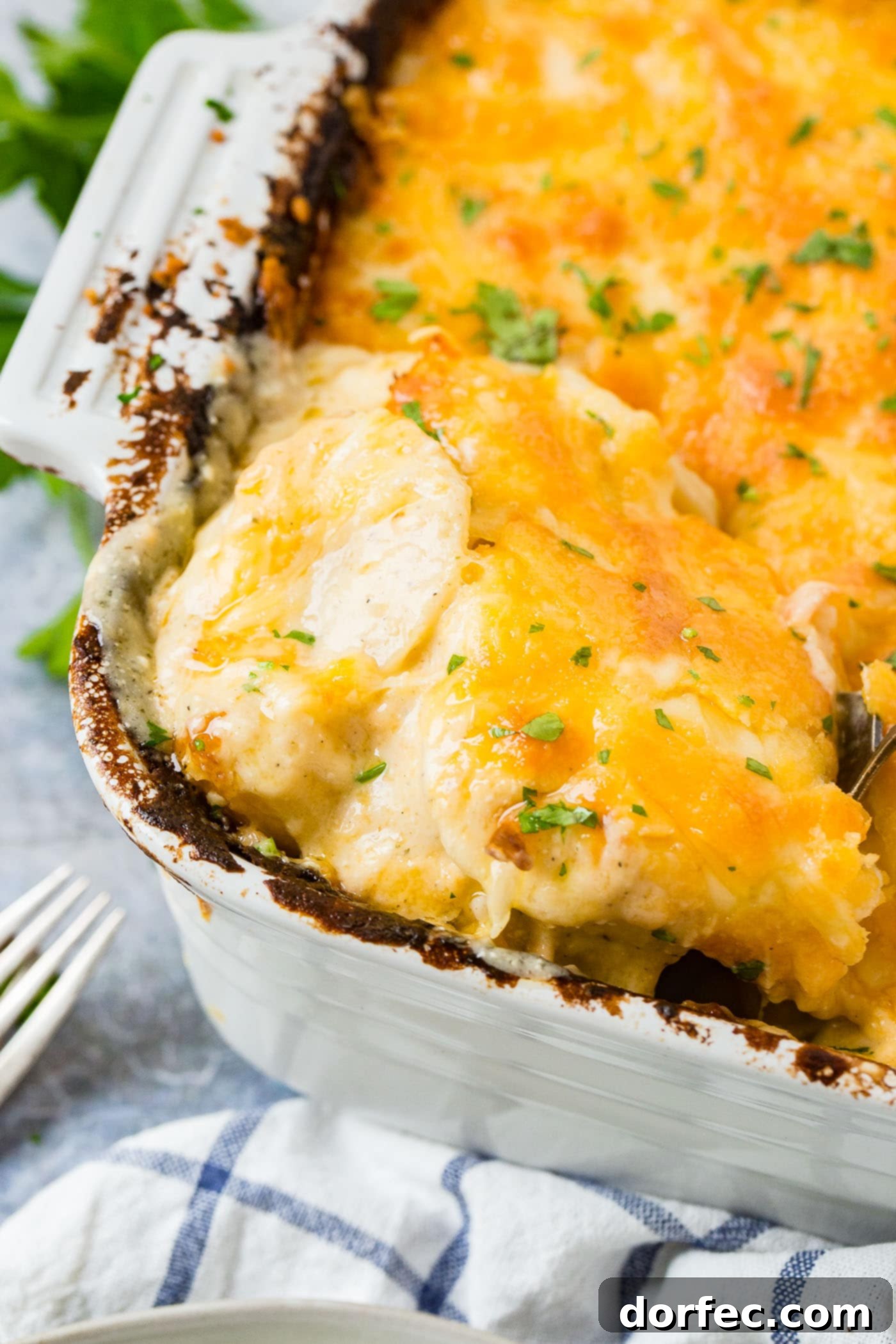 The Ultimate Cheesy Potato Casserole 7 A white casserole dish filled with a bubbling, golden-brown cheesy potato casserole, freshly out of the oven.