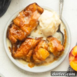 a small dessert plate with three golden baked peach dumplings topped with a melting scoop of vanilla ice cream