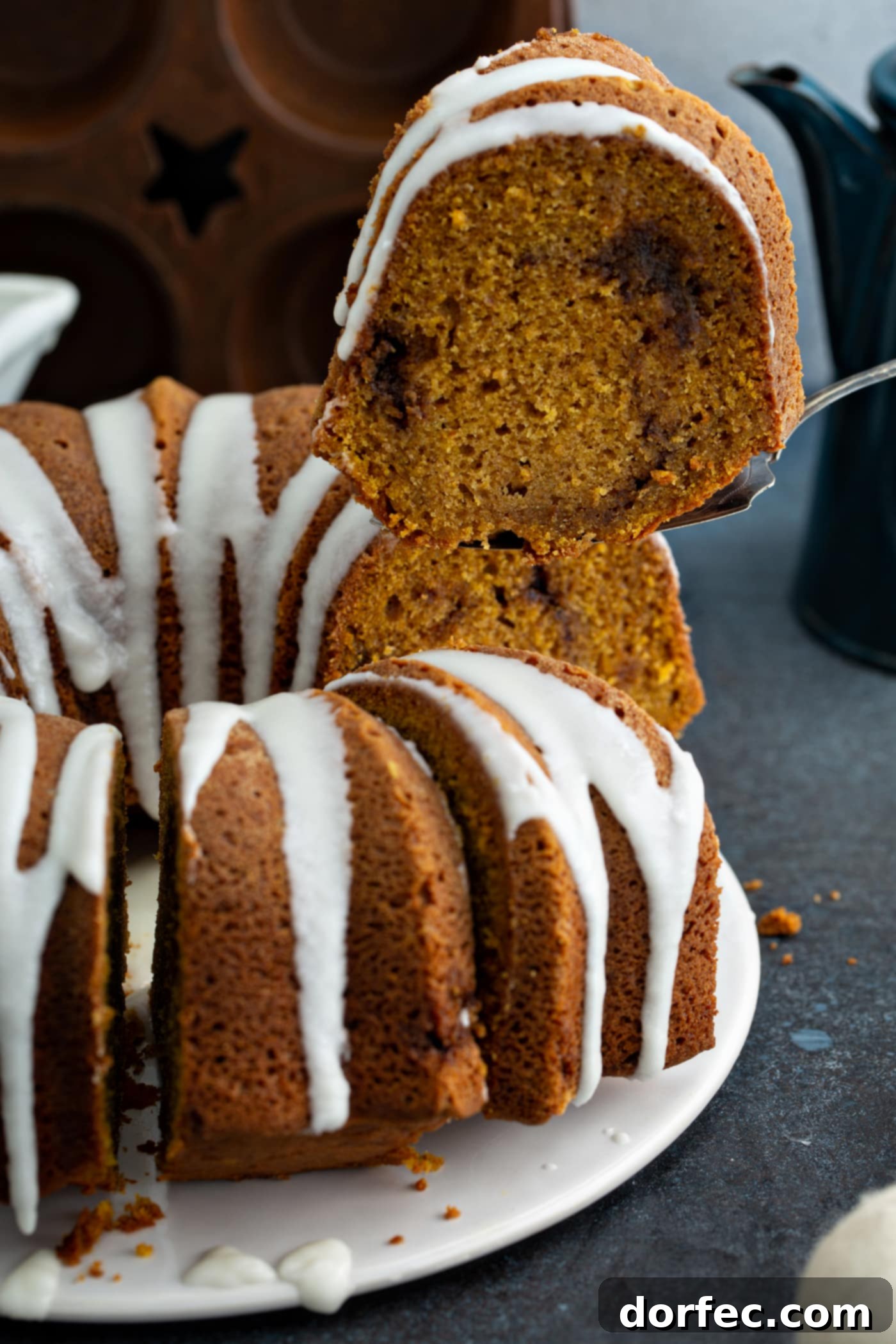 Sour Cream Cinnamon Swirl Pumpkin Bundt Cake A sour cream cinnamon swirl pumpkin bundt cake that has a drizzle of glaze on top. A slice of cake is being removed with a cake server. You can see a rich cinnamon swirl in the middle of the cake.