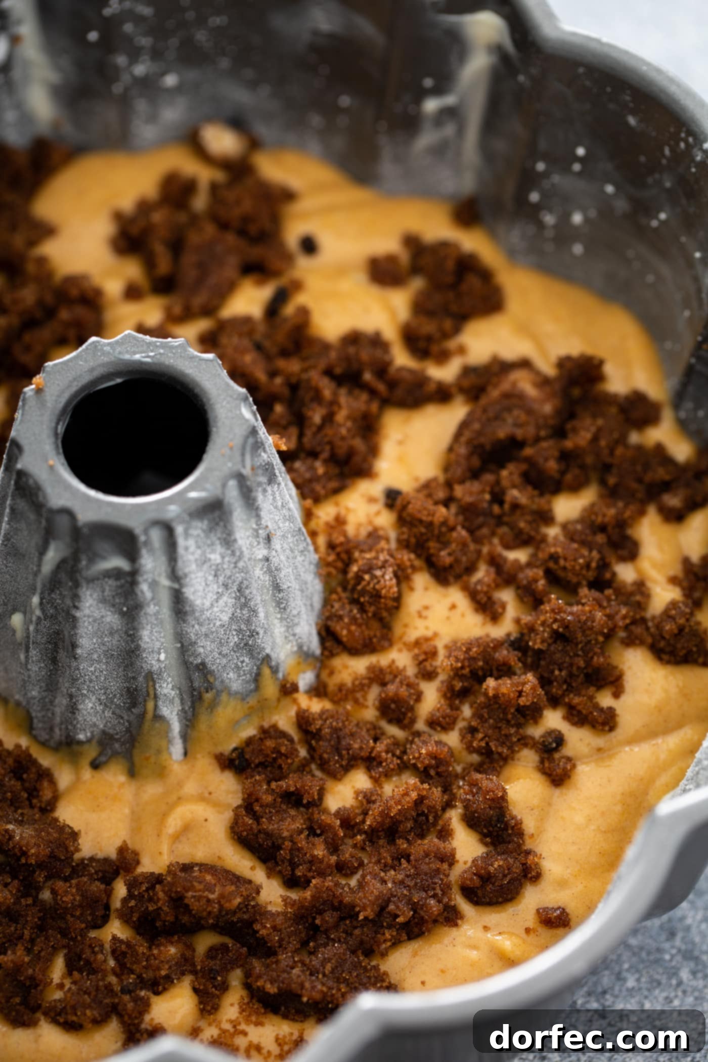 Sour Cream Cinnamon Swirl Pumpkin Bundt Cake An unbaked pumpkin bundt cake in a bundt pan with cinnamon filling on top.