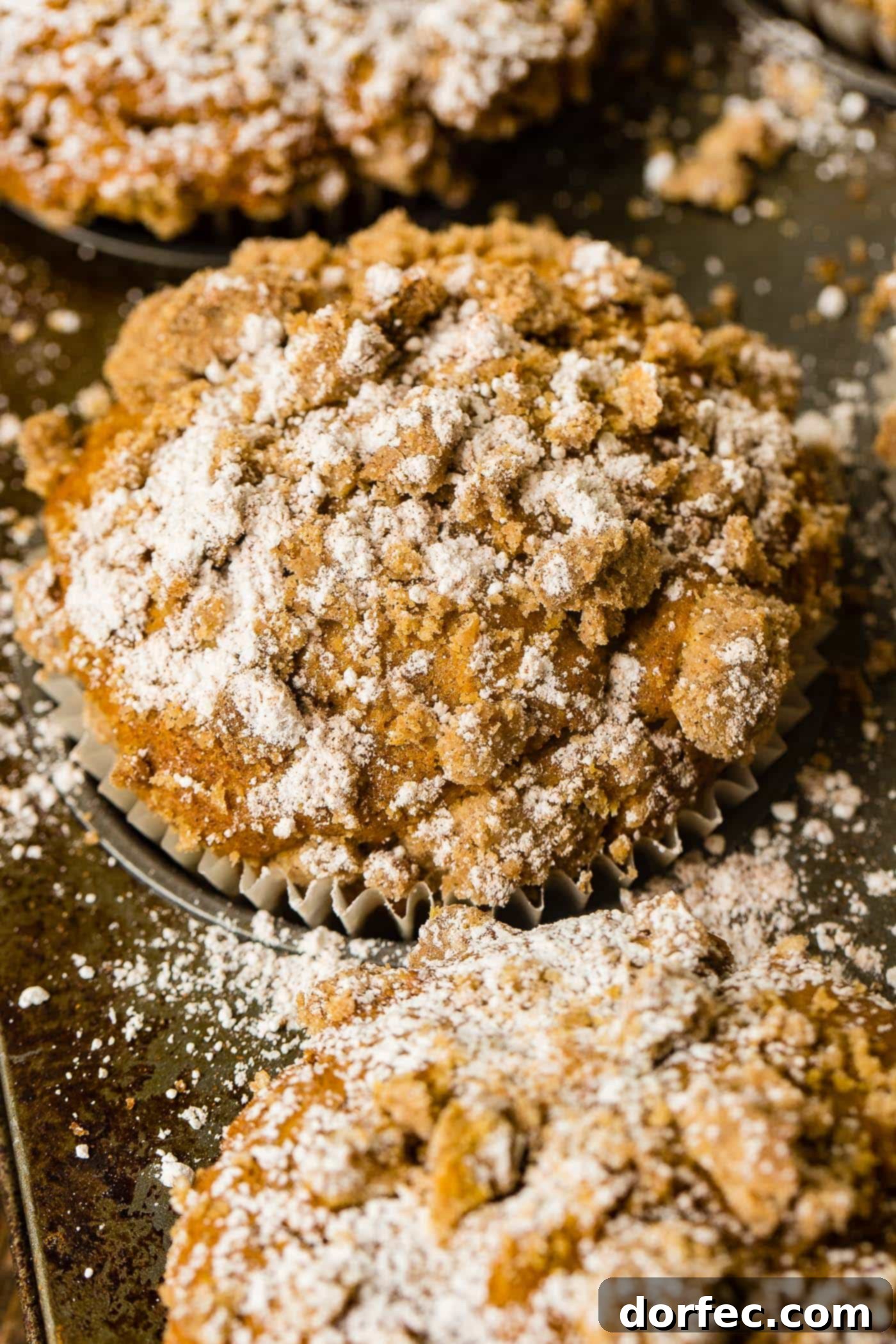 A delicious jumbo pumpkin streusel muffin, garnished with powdered sugar, beckoning with its warm, autumn flavors.