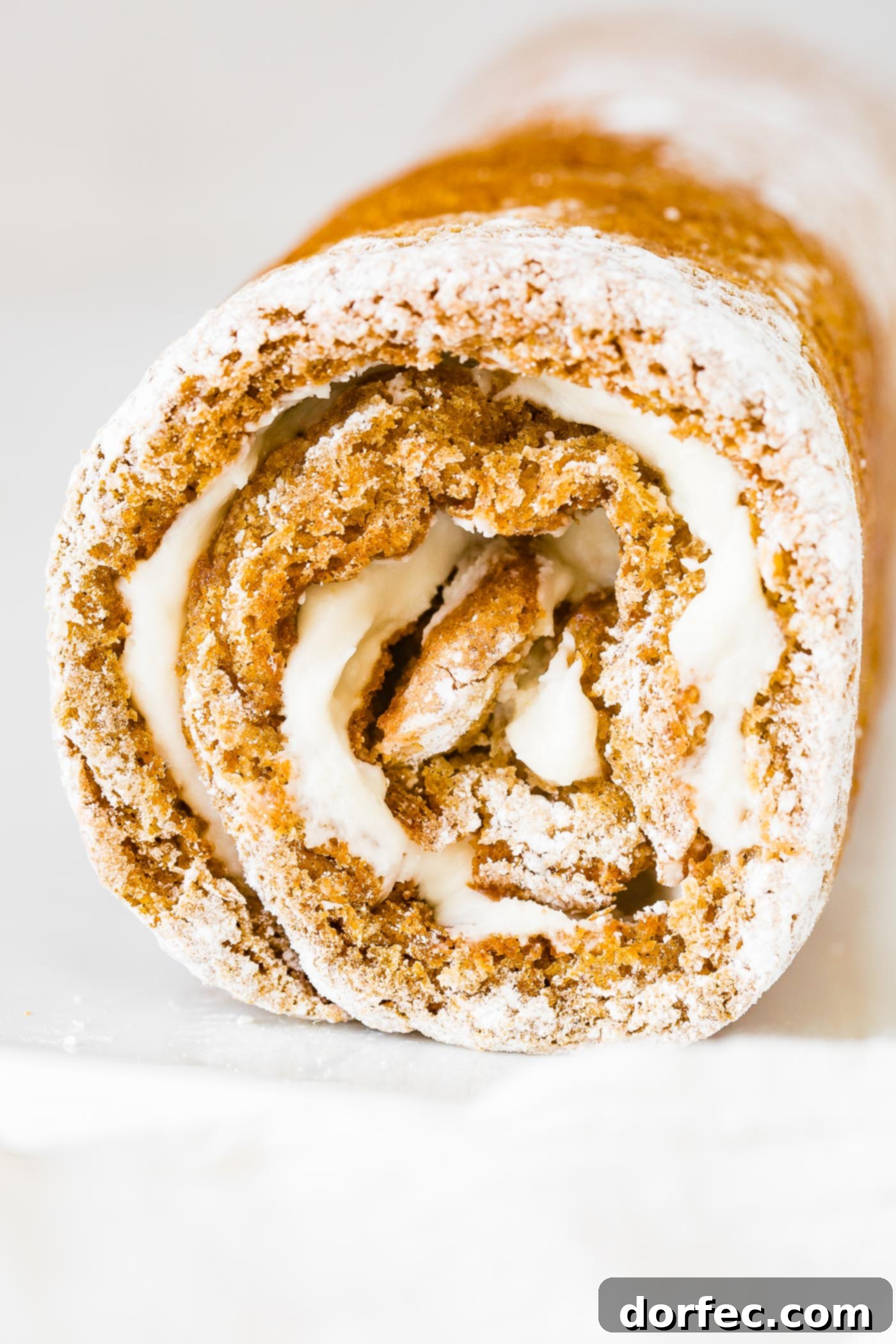 A photo of a pumpkin roll that has just been skillfully rolled, before it is sliced or garnished, highlighting its perfect spiral shape.