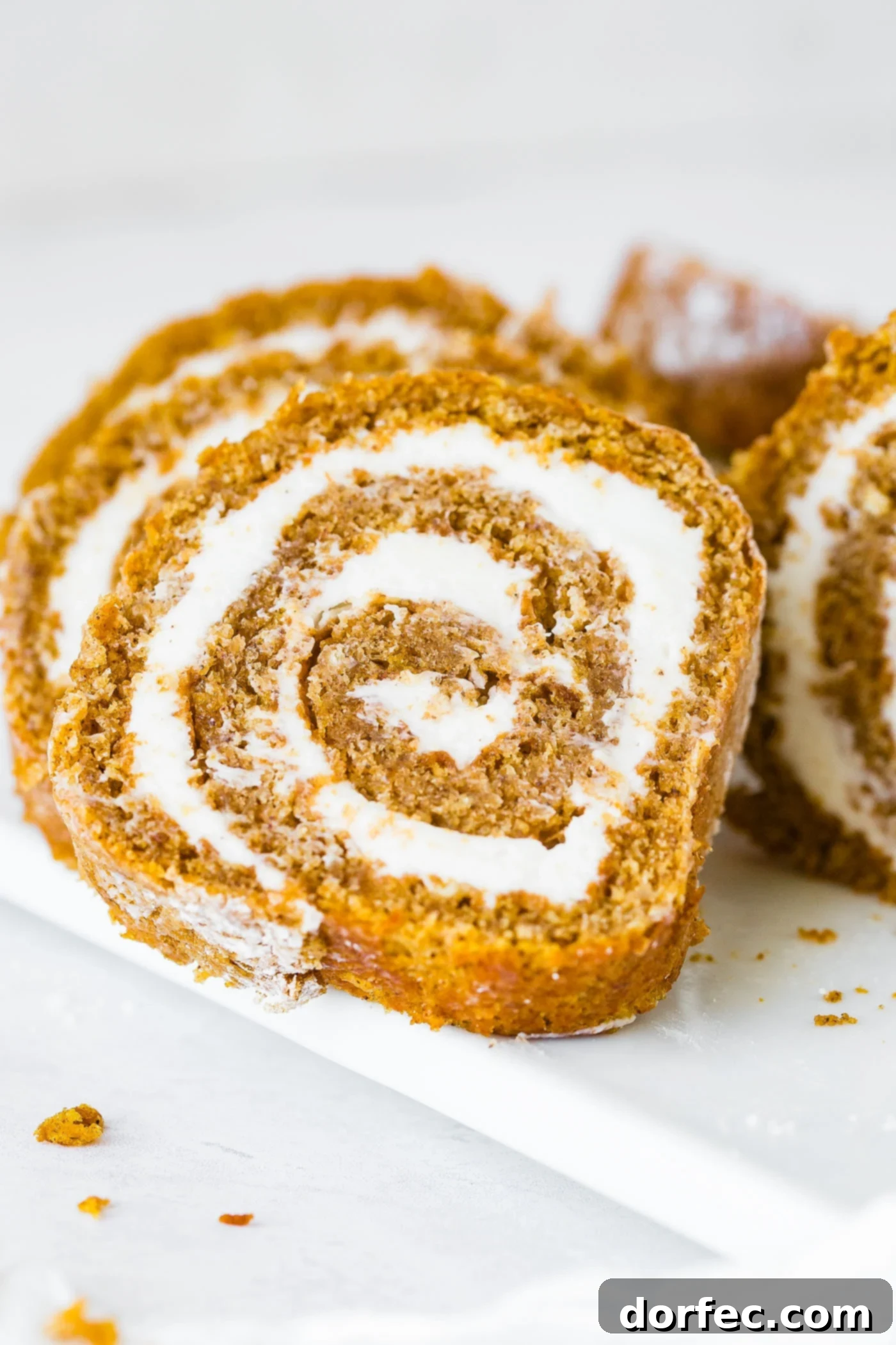 A stunning arrangement of multiple pumpkin roll slices, each showcasing the creamy white filling and moist cake, ready to be served.