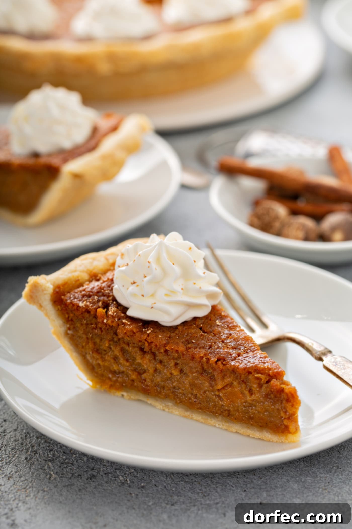 Southern Charm Sweet Potato Pie 11 A photo of a slice of sweet potato pie with a dollop of whipped cream on top sitting on a white plate.