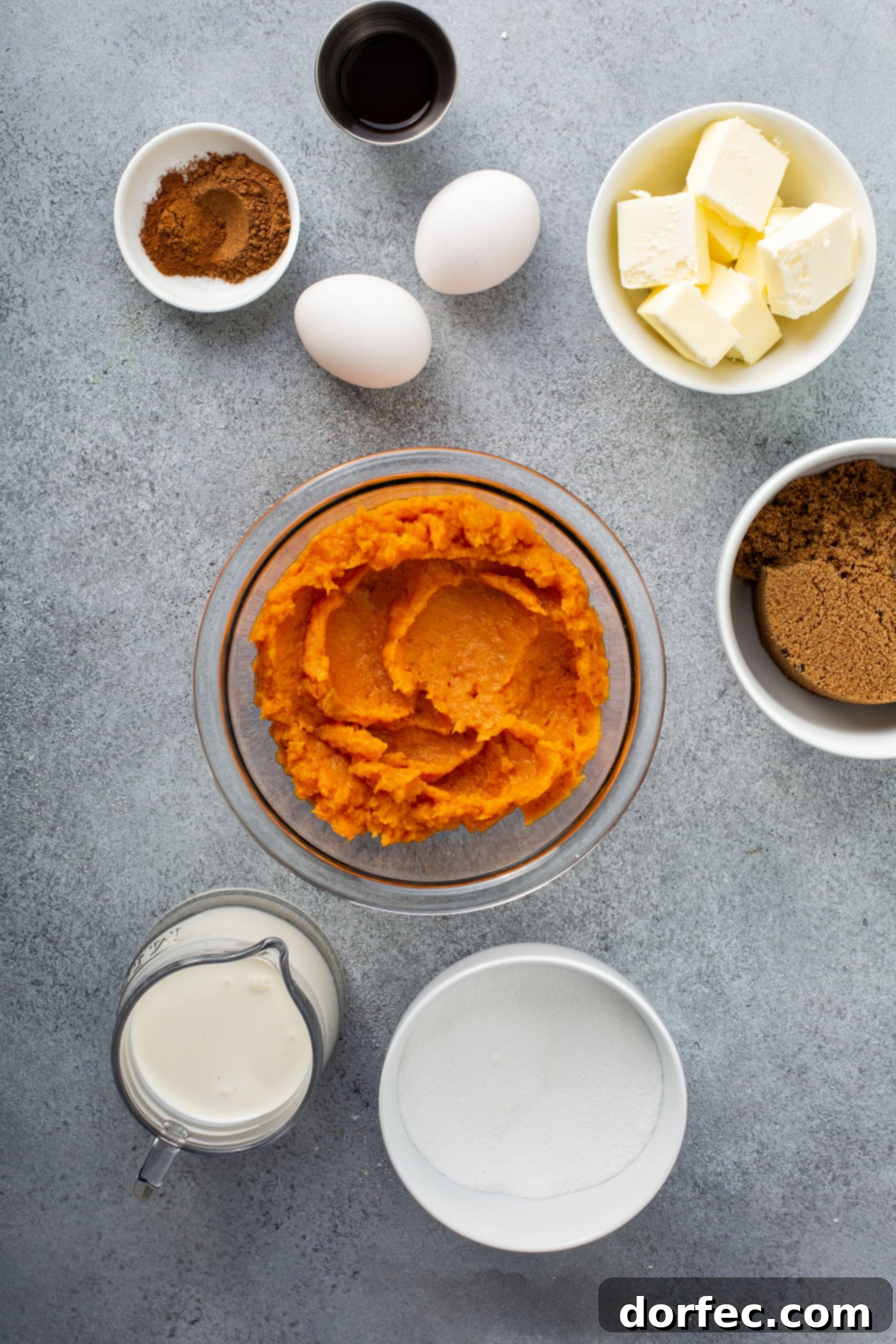 Southern Charm Sweet Potato Pie 3 A photo of all the ingredients for sweet potato pie in separate bowls - pureed sweet potatoes, dark brown sugar, butter, two eggs, vanilla, sugar, cream, and cinnamon.