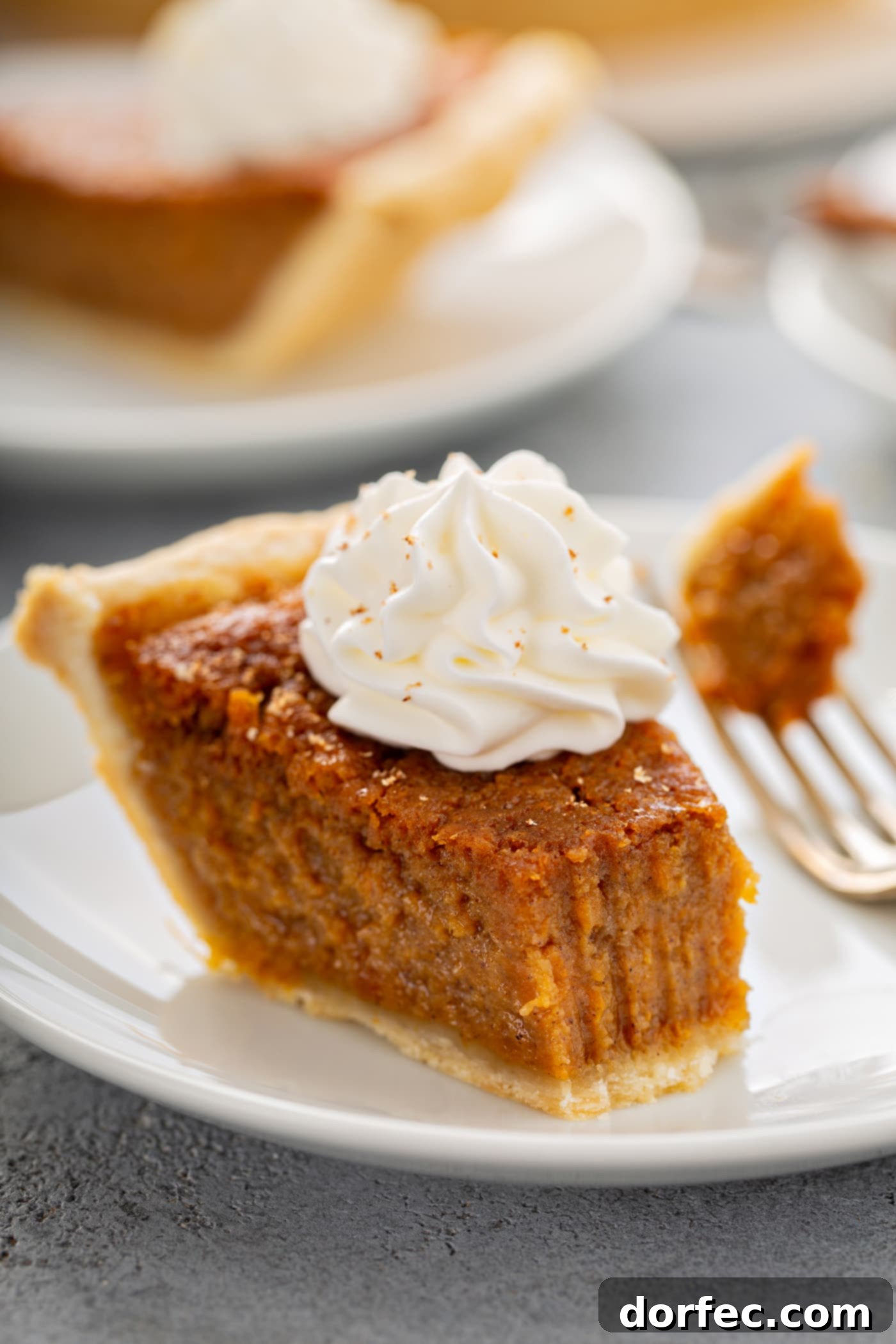 Southern Charm Sweet Potato Pie 8 A photo of a bite of sweet potato pie being removed from a slice with a fork.
