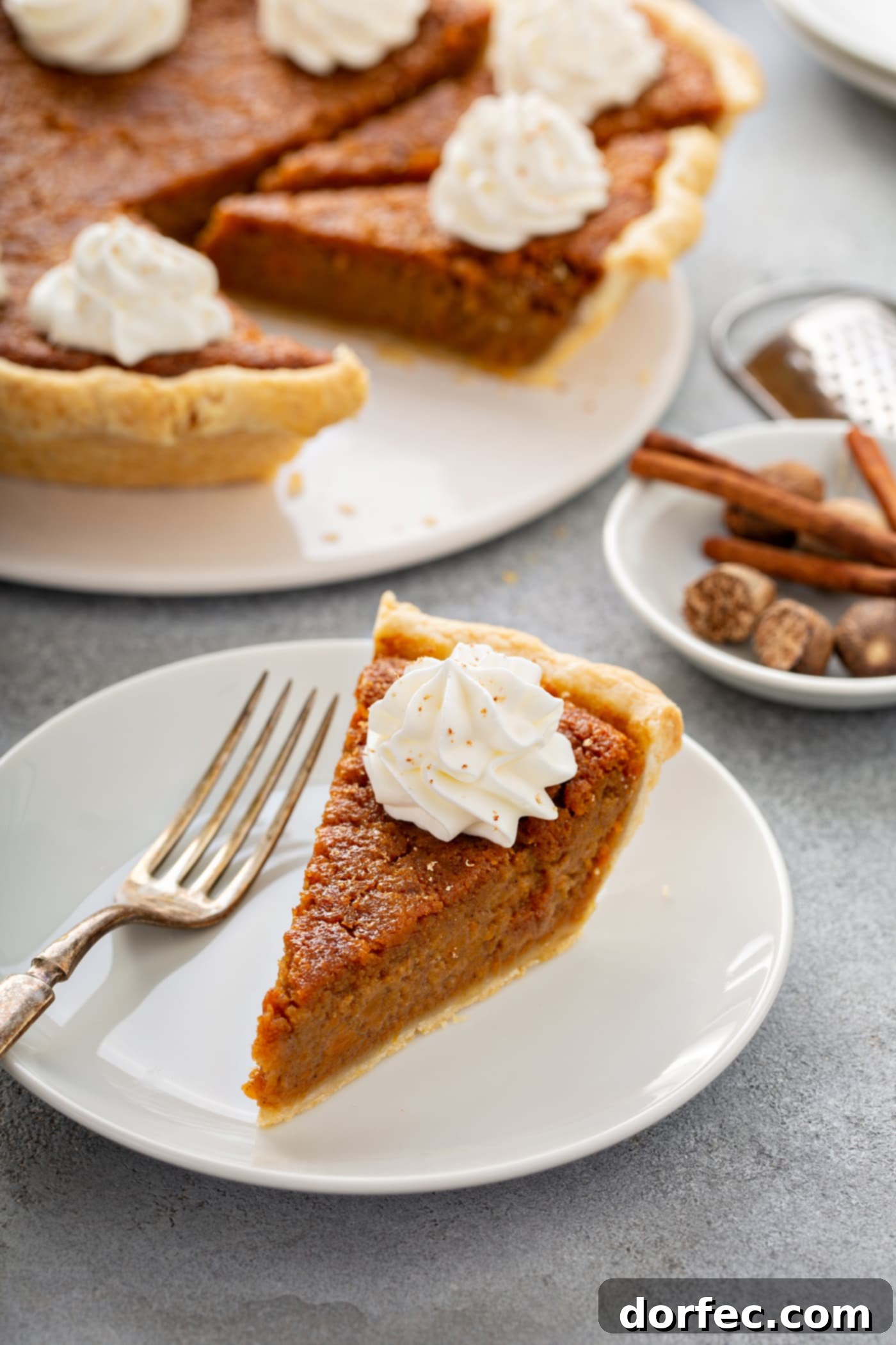 Southern Charm Sweet Potato Pie 10 A photo of a slice of sweet potato pie sitting on a white plate with the whole sweet potato pie in the background.
