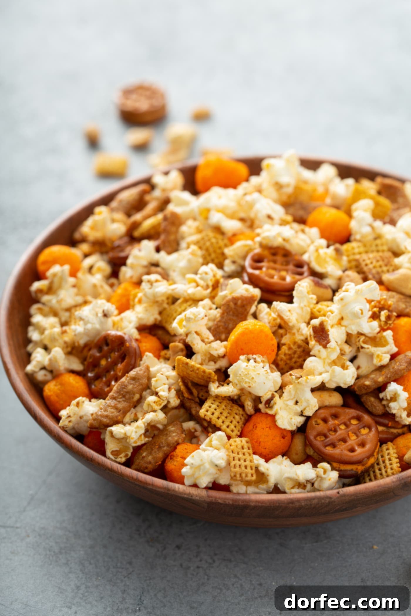 A vibrant bowl of March Madness snack mix, featuring a delicious assortment of popcorn, cheese balls, crunchy pretzels, savory peanuts, and crispy sesame sticks.