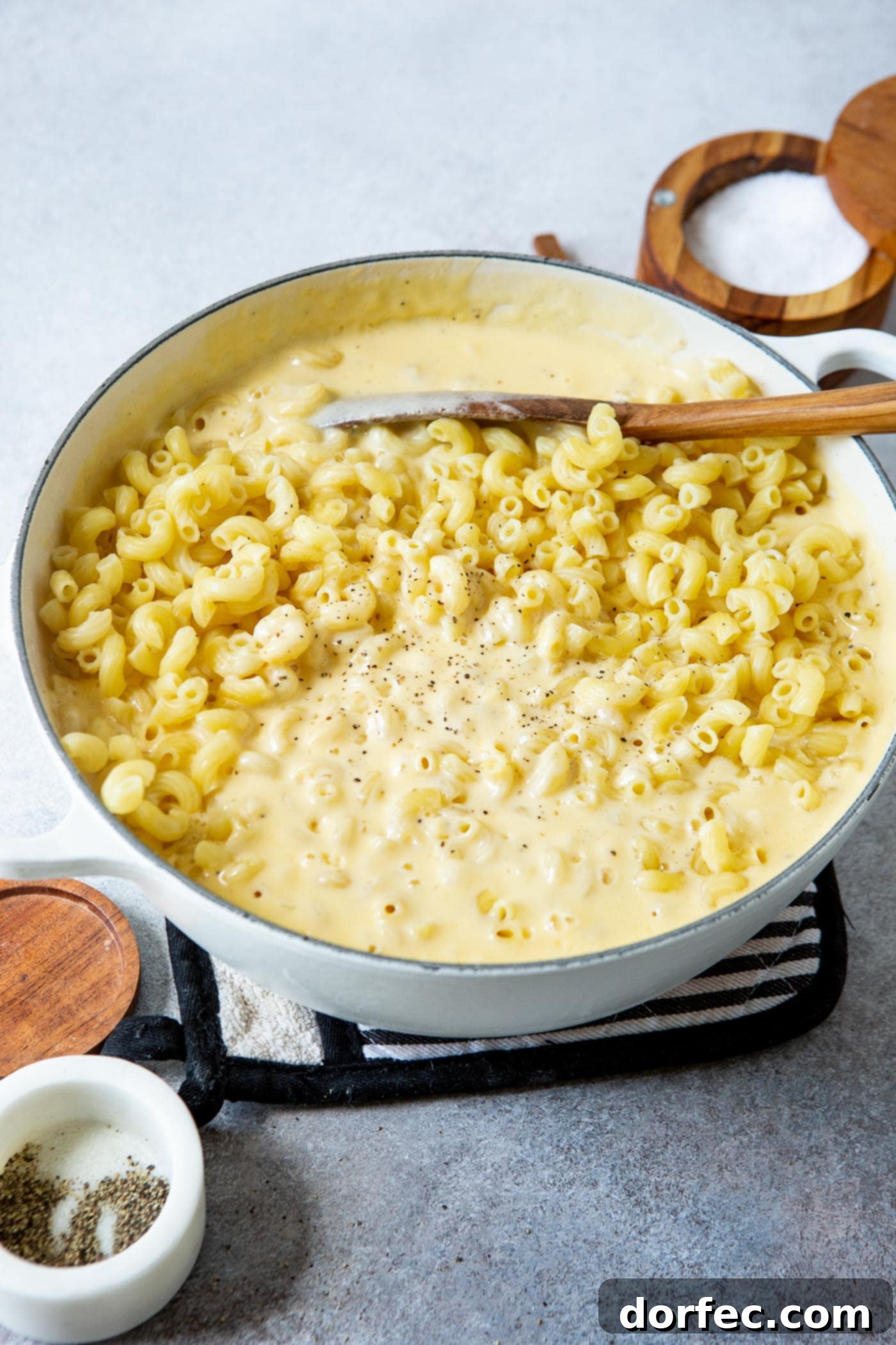 Best Macaroni and Cheese Ever A pan with macaroni, cheese sauce and a wooden spoon.