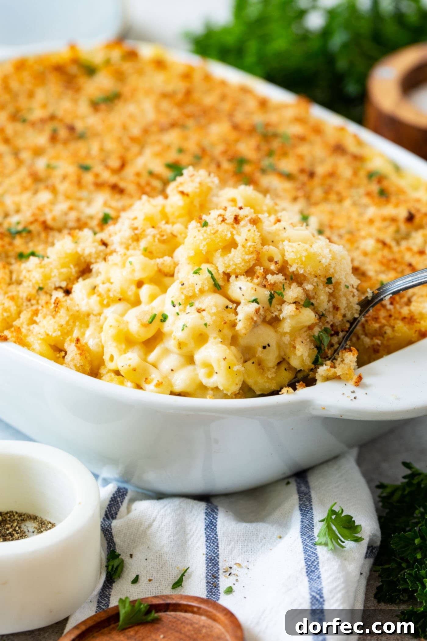 Best Macaroni and Cheese Ever A casserole dish with baked mac and cheese. The mac and cheese is topped with browned bread crumbs and has a spoon in it.