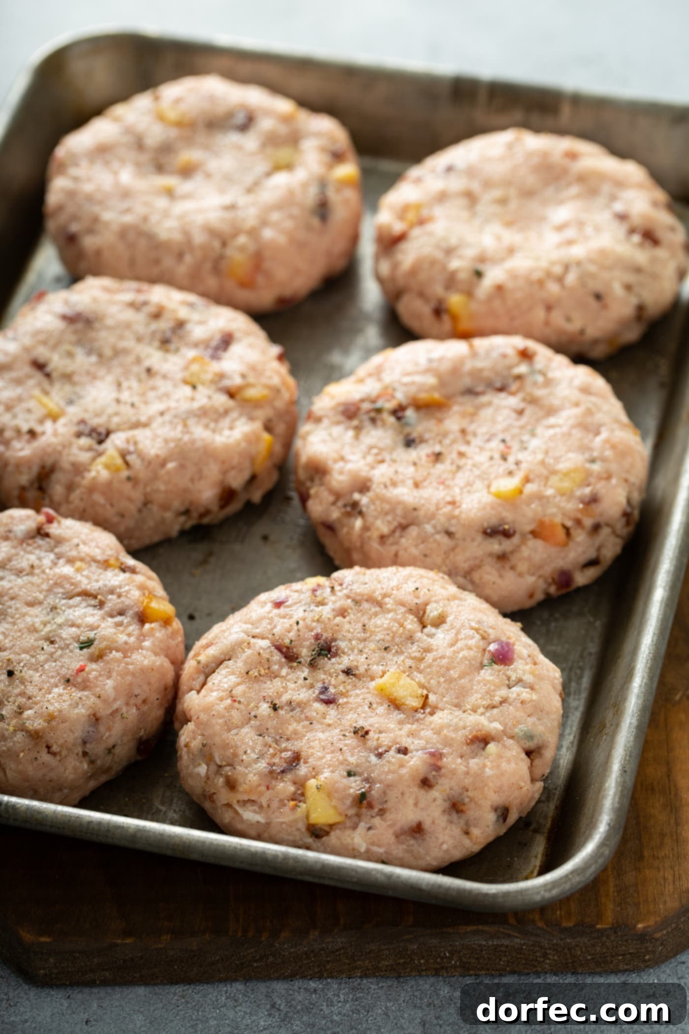 6 chicken burger patties on a baking pan.