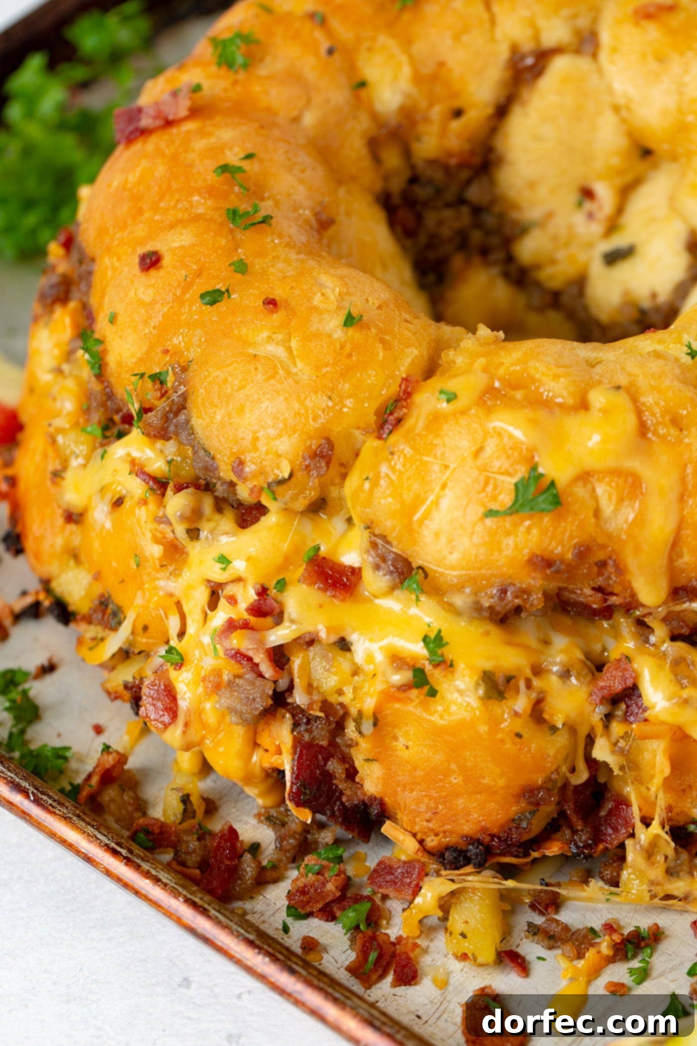 Breakfast Sausage and Apple Cheesy Pull Apart Savory sausage pull apart bread generously topped with melted cheese, revealing flavorful pieces of bacon and sausage embedded within the soft bread.