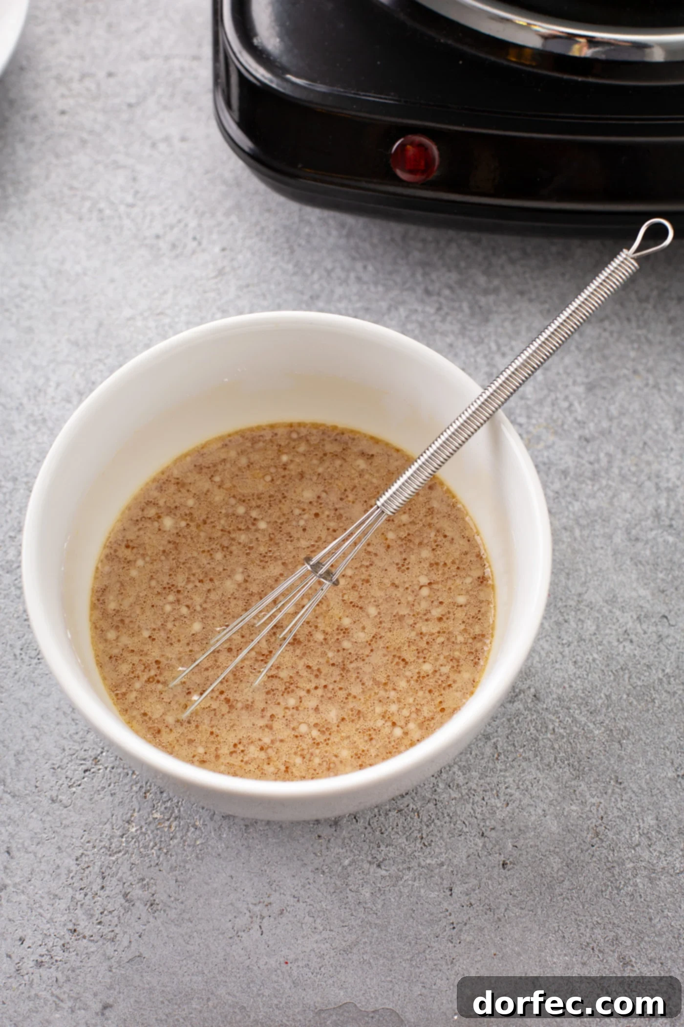 Easy Egg Drop Soup A bowl with a whisk and ingredients for the soup.