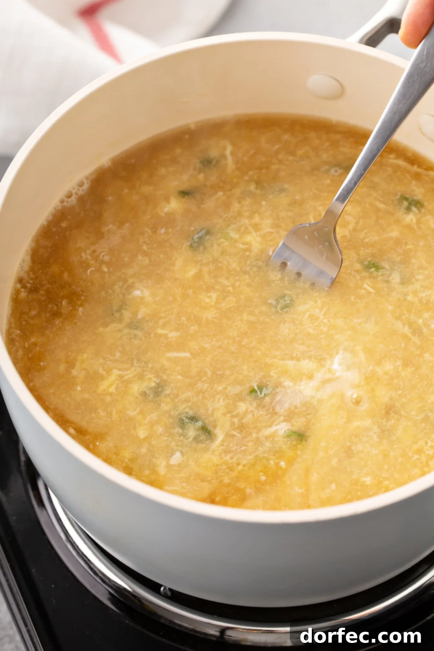 Easy Egg Drop Soup A bowl of egg drop soup with a fork resting in it.