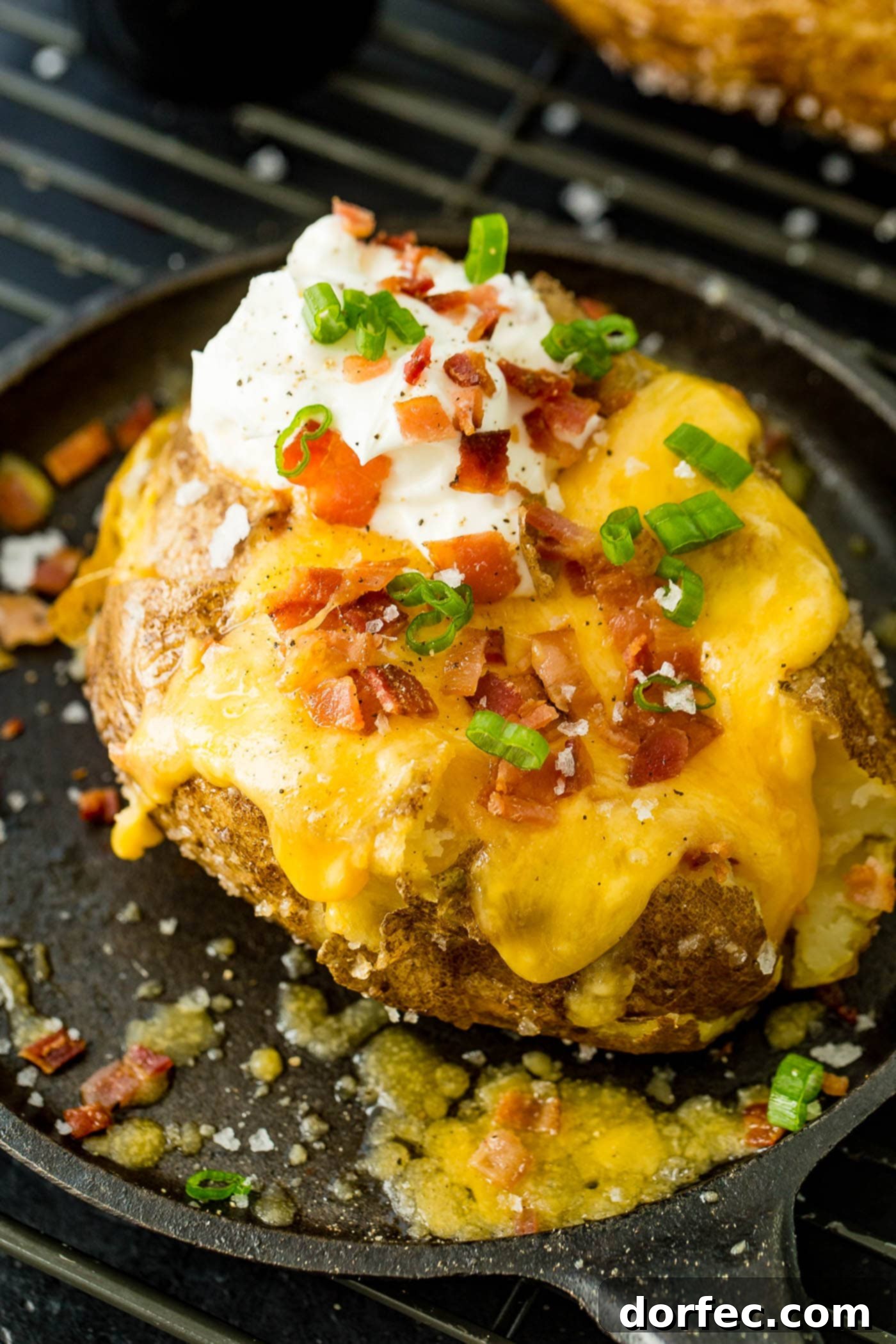 Fluffy Inside, Crispy Outside: The Best Oven Baked Potatoes 5 a loaded baked potato with cheese, sour cream, butter, bacon and green onions