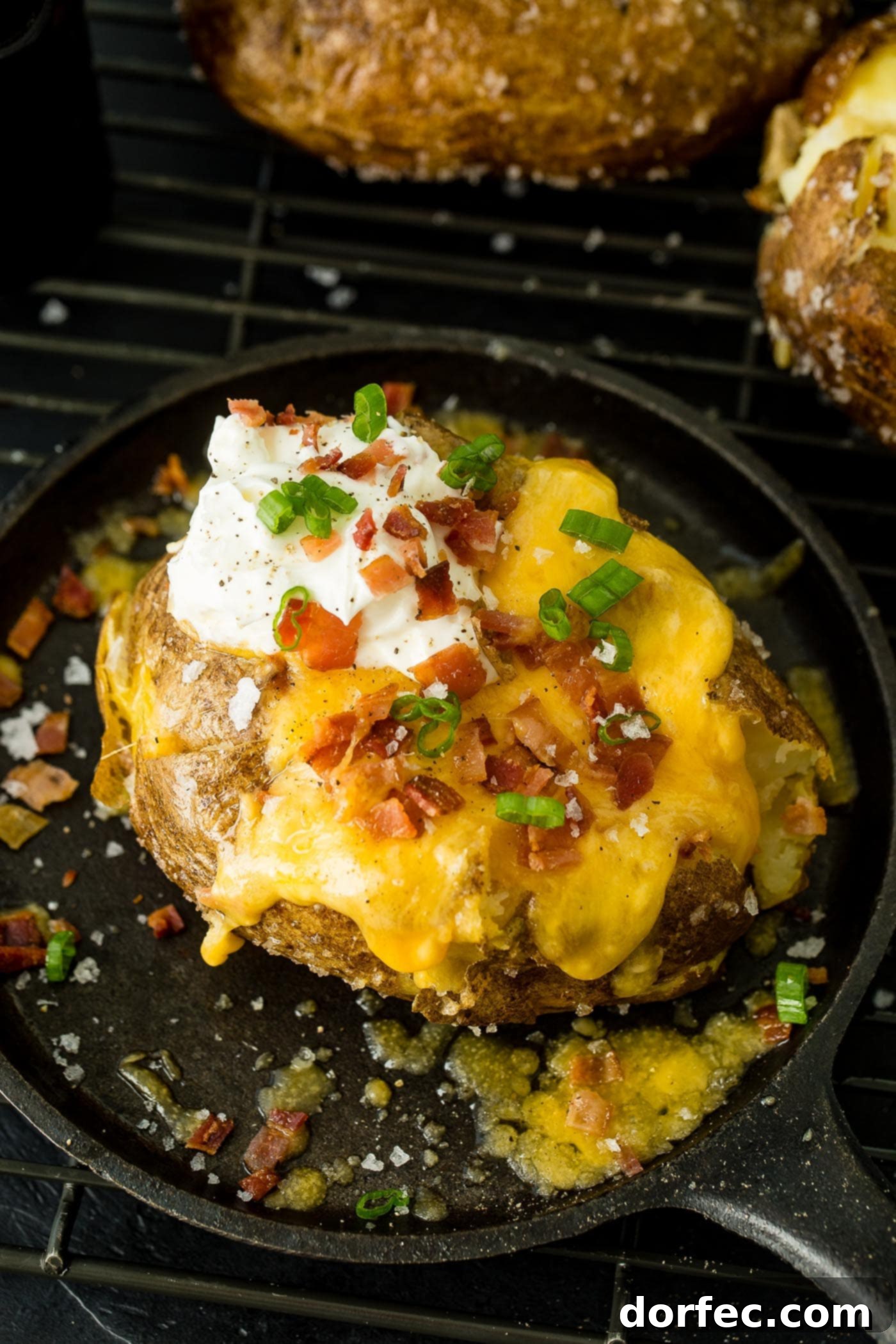 Fluffy Inside, Crispy Outside: The Best Oven Baked Potatoes 7 a loaded baked potato with cheese, sour cream, butter, bacon and green onions